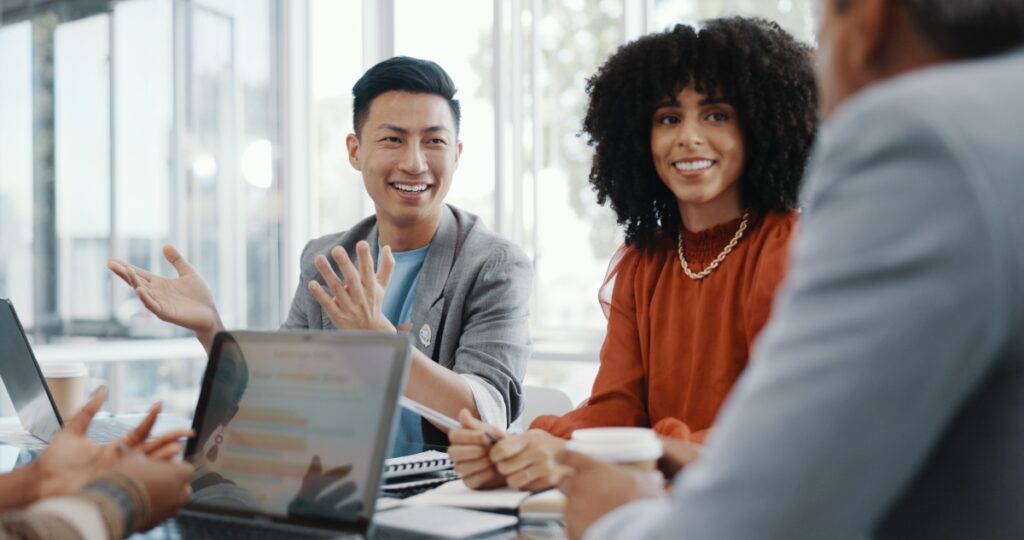 Man and woman sitting at a conference table, smiling during a group meeting.