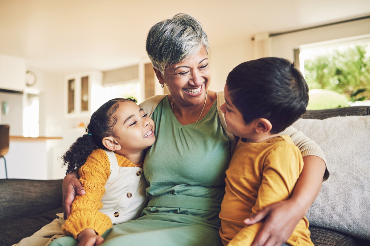 Woman embracing two children, all smiling.